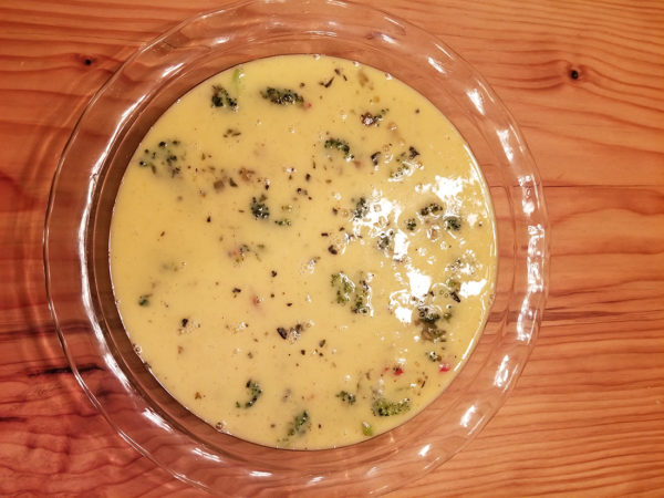 Pour the beaten eggs over the vegetable in the pie pan.